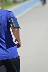 Fototapeta premium Athlete jogging with a bandage and a phone on her arm