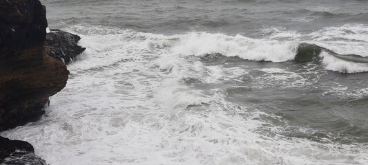 The waves of the sea are crashing against the rocks on a stormy day.