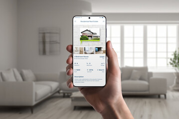 Real estate app on phone display in man hand. Property listings for an effortless home search experience
