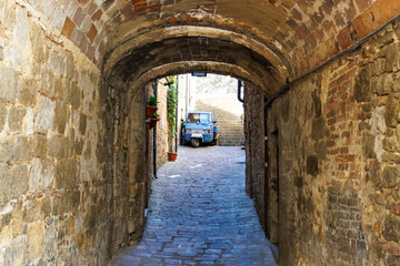 Fototapeta premium Old center of Volterra with a narrow arched street and a Ape, Tuscany, Italy, Europe