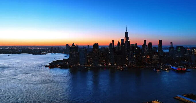 Manhattan switching on lights in the evening. Beautiful scenery of New York with blue-orange sky at backdrop.