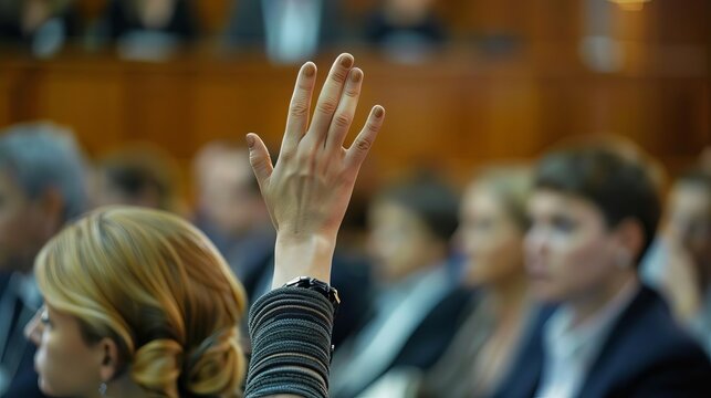 A woman raising her hand to speak during a QA session at a business strategy seminar
