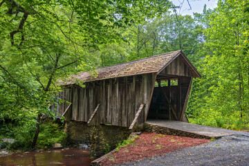 Horizontal, Pisgah covered bridge, A historic wooden bridge with a shake shingle roof, built 1911 spans the West Fork of Little River. Asheboro, Randolph County, NC. late spring, greenery everywhere. 