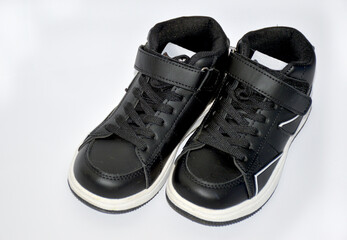 children's sneakers in black with a white stripe on the sole on a white background. light and comfortable shoes for sports and outdoor walks. stylish and fashionable shoes