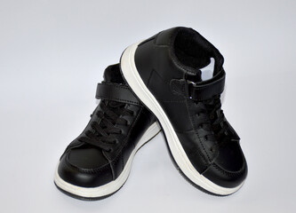 children's sneakers in black with a white stripe on the sole on a white background. light and comfortable shoes for sports and outdoor walks. stylish and fashionable shoes