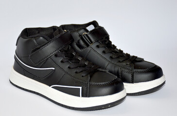 children's sneakers in black with a white stripe on the sole on a white background. light and comfortable shoes for sports and outdoor walks. stylish and fashionable shoes