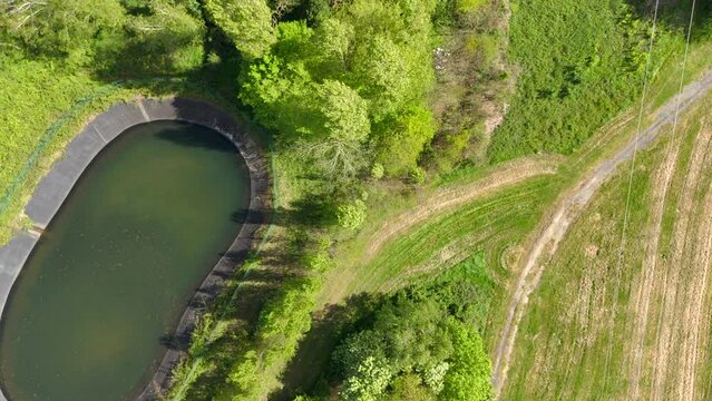 Top-down aerial view of an artificial pond and grassy paths near Rennes, France