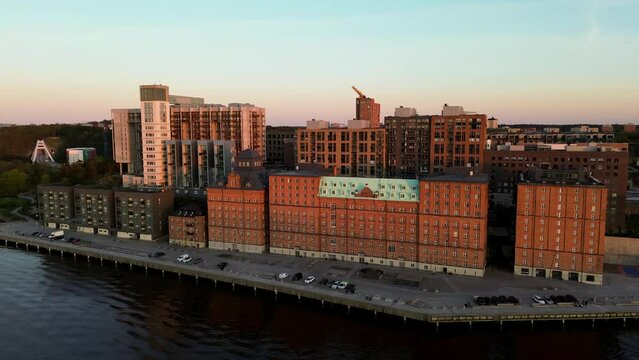 Panning aerial view of Kvarnholmen, residential district in Nacka, Sweden, a suburb of Stockholm, in sunset evening light with industrial style brick buildings by the sea
