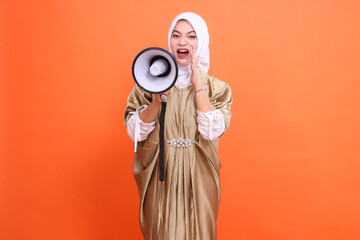 gesture of mature Asian woman screaming holding loudspeaker megaphone palm to mouth wearing kaftan...