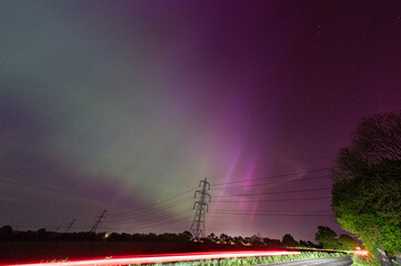 Car tail lights in front of the northern lights, aurora borealis, from Stansted, Essex, UK. The...