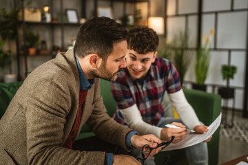 Adult professor mentor and young student read together lesson at home