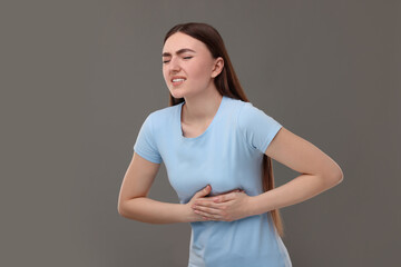 Woman having heart attack on grey background