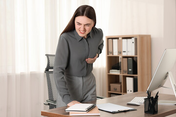 Woman having heart attack near table in office