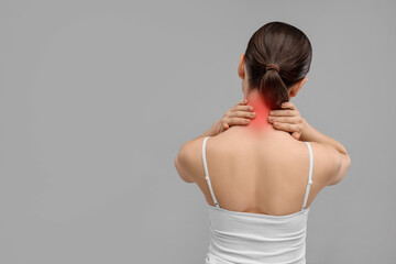 Woman suffering from neck pain on grey background, back view