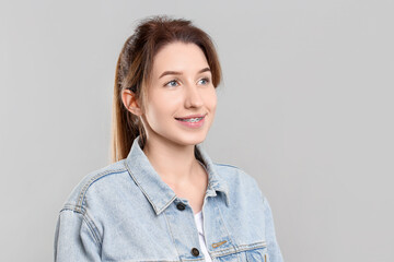 Obraz premium Portrait of smiling woman with dental braces on grey background