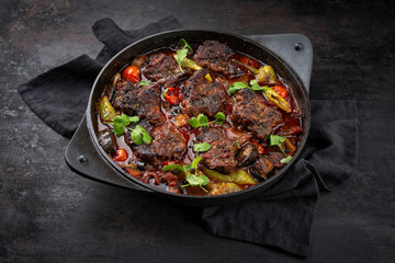 Traditional Greek braised lamb stew with vegetables and olives in a hearty meat sauce with red wine served as a close-up in a designer casserole with text space