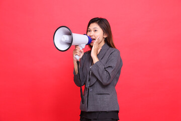 Asian office girl expression tilted to the top right, shouting cheerfully, using a megaphone, hands...