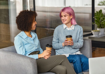 Smiling African American businesswoman and Caucasian coworker working over laptop at creative office