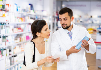 Male pharmacist consulting woman buyer about hair care product in drugstore.