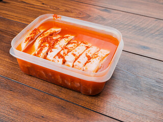 Pork chops in red Asian style marinade with chilly pepper in plastic container. Fine pork meat for...