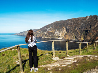 Teenager girl on a trip to Slieve League Cliff, Ireland. Stunning nature scenery with cliff, ocean...