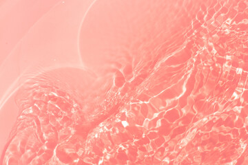 Red water bubbles on the surface ripples. Defocus blurred transparent pink colored clear calm water surface texture with splash and bubbles. Water waves with shining pattern texture background