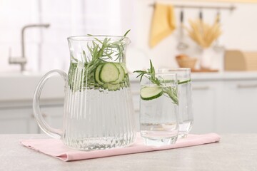 Refreshing cucumber water with rosemary on table in kitchen