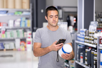 Male shopper scanning a QR code using a mobile phone in a hardware store