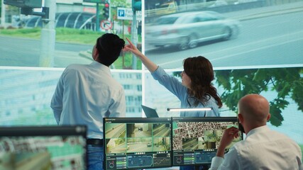 Diverse employees monitoring traffic via radar cameras at stop lights, using surveillance CCTV...