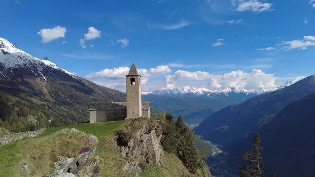 The chapel of San Romerio standing  on cliff drop-off above mountain overlooking the  Val Poschiavo valley in Switzerland. 