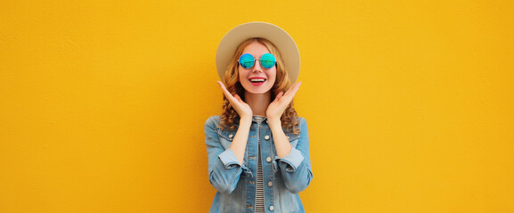 Portrait of stylish happy surprised young woman in summer straw hat, glasses on orange background