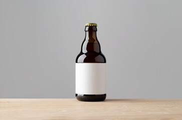 Amber steinie beer bottle mockup with blank label on a wooden table.