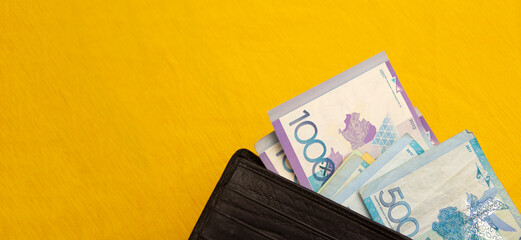 Horizontal banner. Black wallet on yellow textile background. Coin and banknote. Paper cash money...