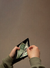 Vertical photo. Man takes out paper American bill of 1 dollar of USA from wallet. Cash money for...