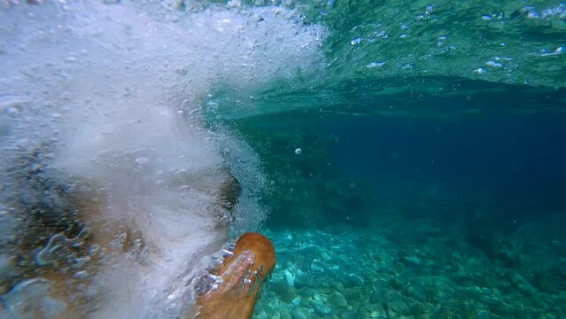 SLOW MOTION: Adventurous dog leaping into crystal clear turquoise sea from a rocky shore. Cute brown doggo enjoys on summer holidays and is always ready to dive into inviting waters of Adriatic Sea.