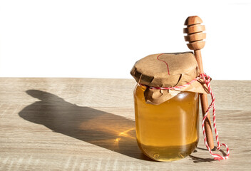 Honey with honey dipper and wooden stick. Organic floral honey on the wooden table with white...