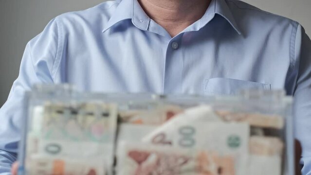 man collecting donations into a transparent donation box.. The act of giving supports charity. Selective focus