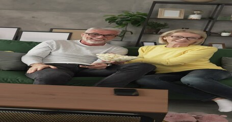 Mature senior couple husband and wife watch movie and eat popcorn - Powered by Adobe