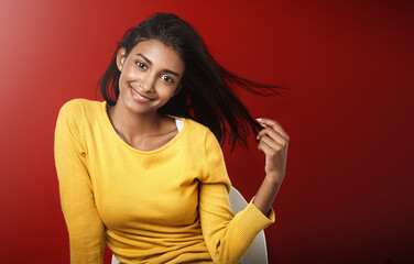 Obraz premium Studio, portrait and happy woman with casual fashion, relax and positive attitude of female person on mockup space. Smile, face and gen z girl with cool style, confidence and pride on red background