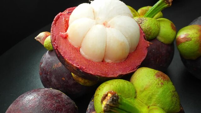 A stunning close-up of a mangosteen reveals its rich, purple exterior and succulent, ivory flesh. The vibrant colors and intricate textures evoke the allure of this exotic tropical treasure.
