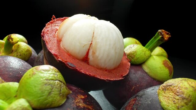 Dive into the world of the mangosteen with a macro shot revealing its lush, purple rind and succulent, ivory flesh. Each segment bursts with flavor, a tantalizing symphony of texture and taste. 
