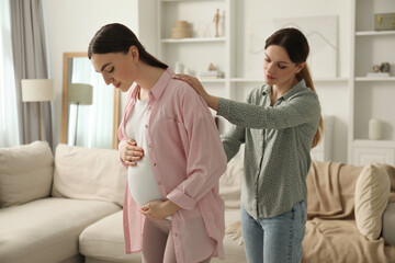 Doula massaging pregnant woman at home. Preparation for child birth