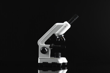 Modern metal microscope on black mirror surface