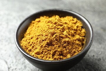 Dry curry powder in bowl on dark table, closeup