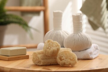 Loofah sponges, soap and herbal bags on wooden table indoors, closeup