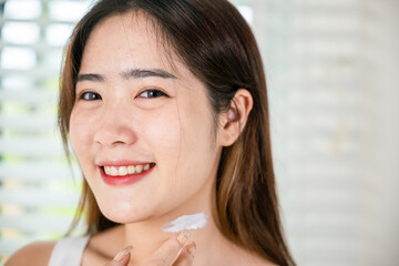 Happy woman smiling apply lotion moisturizer on her neck after shower, Asian beautiful young female...