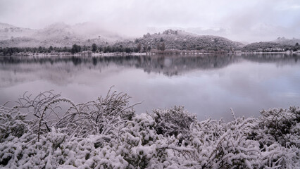 Magical alpine landscape. Long exposure shot of the lake, mountains and forest covered with snow in winter at sunrise. 