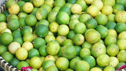 Limes in bamboo basket. Some are green and some are yellow. Focus selected