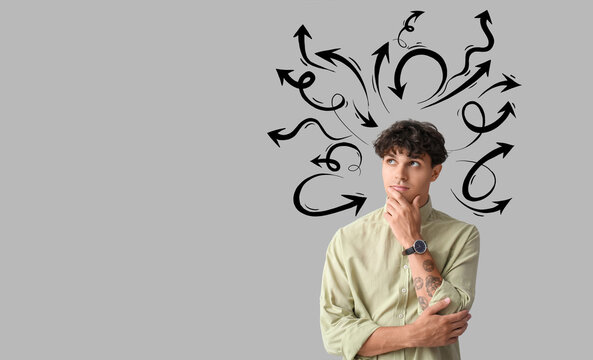 Portrait of pondering young man on grey background