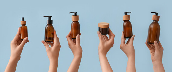 Hands holding different cosmetic products on light blue background